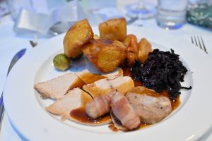 A close up image of a plate of food, including roast potatoes, turkey and pigs in blankets.
