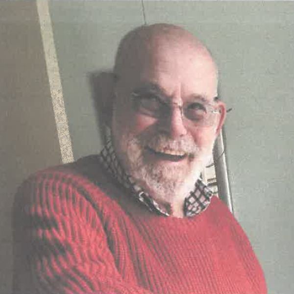 A man with a white beard and moustache, wearing a red jumper.