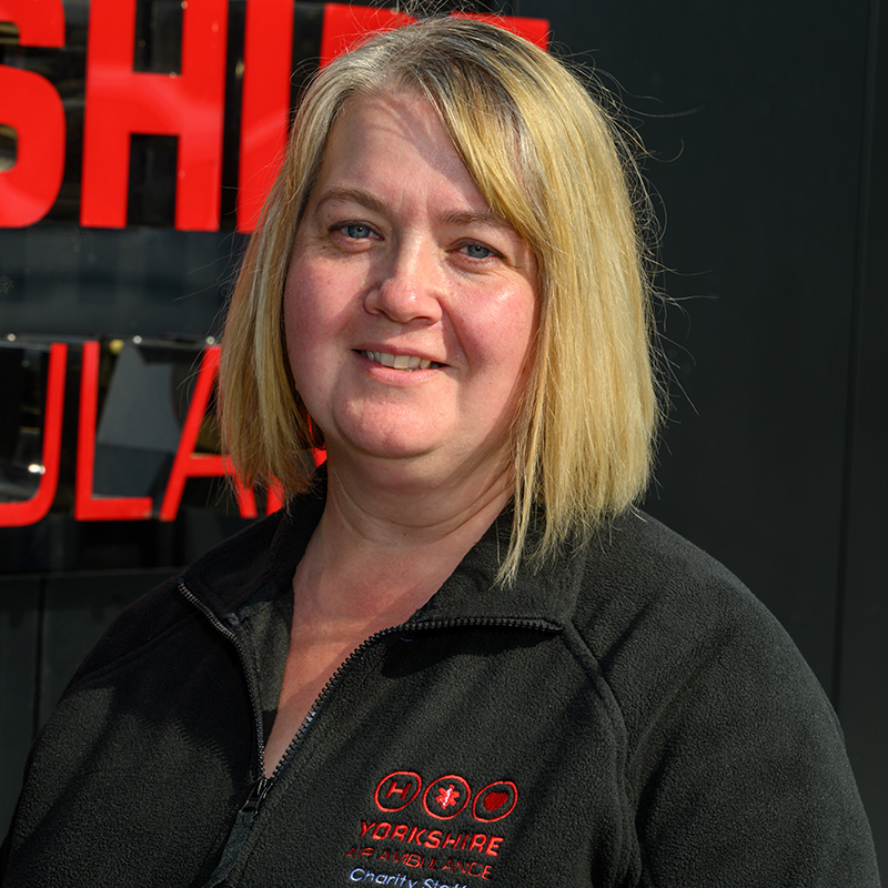 A lady with a blonde bob hair style and wearing a black fleece with a red logo