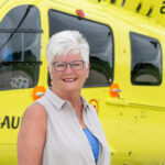 Woman in front of a helicopter smiling