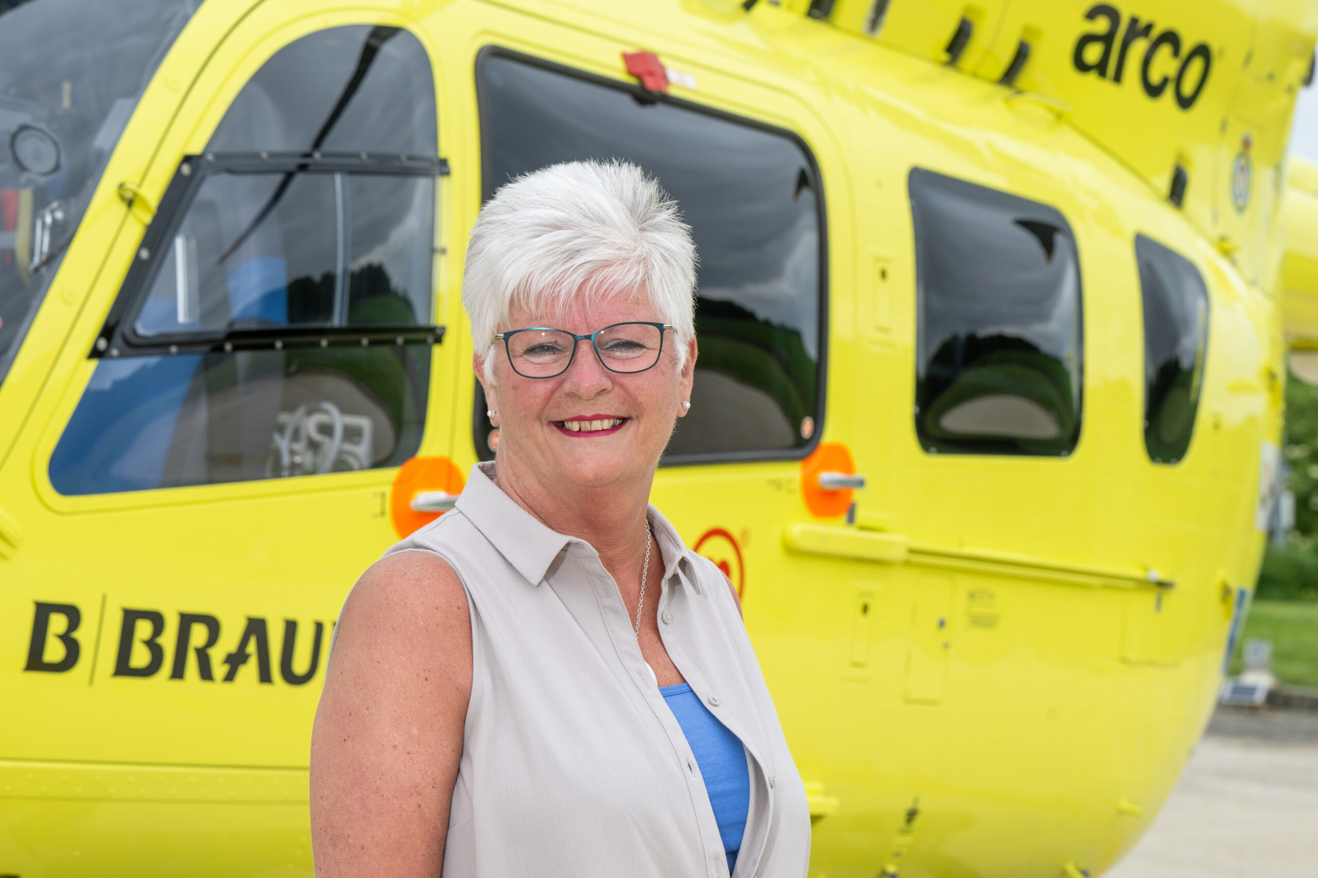 Woman in front of a helicopter smiling